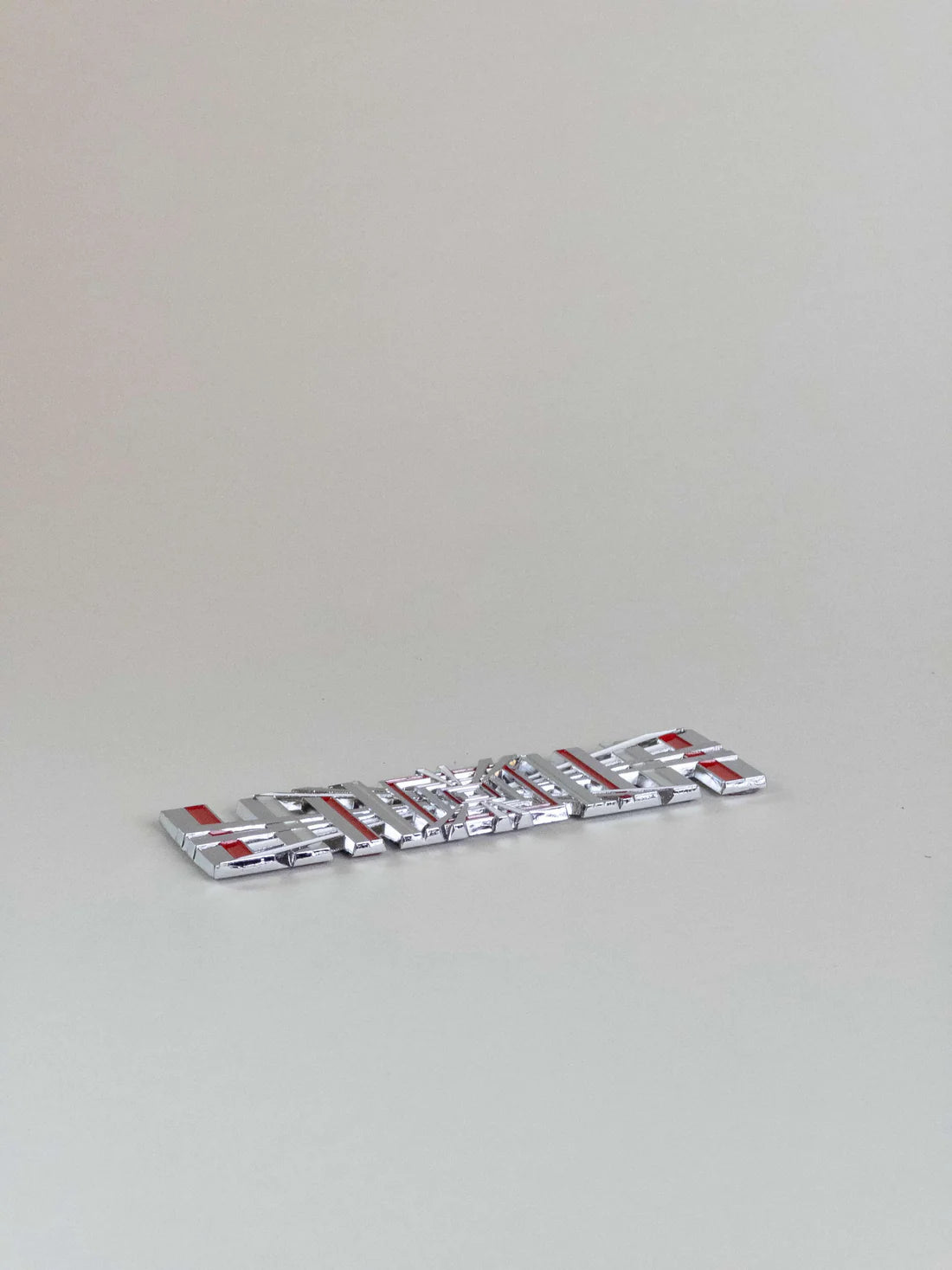 närbild på detaljer och material av Tesla Plaid Emblem/Badge Silver – TESLA