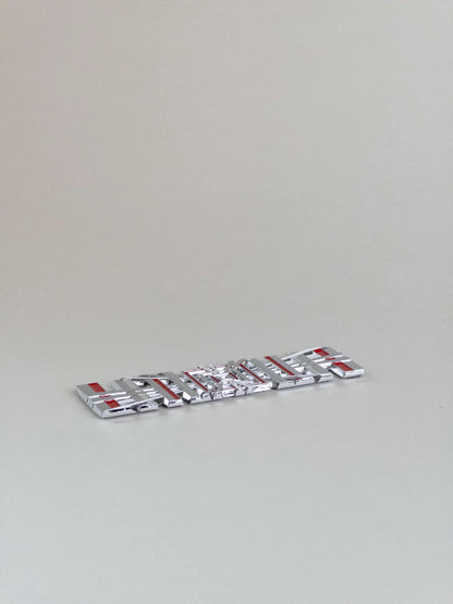 närbild på detaljer och material av Tesla Plaid Emblem/Badge Silver – TESLA